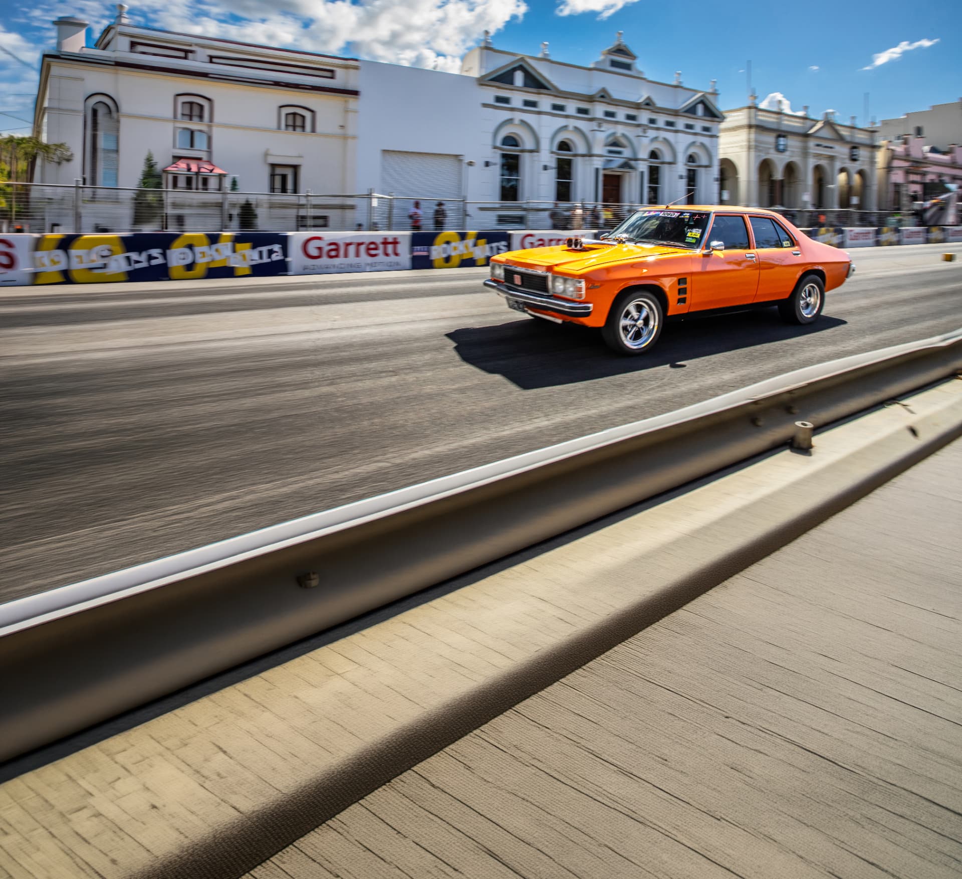 Orange classic muscle car racing through city streets